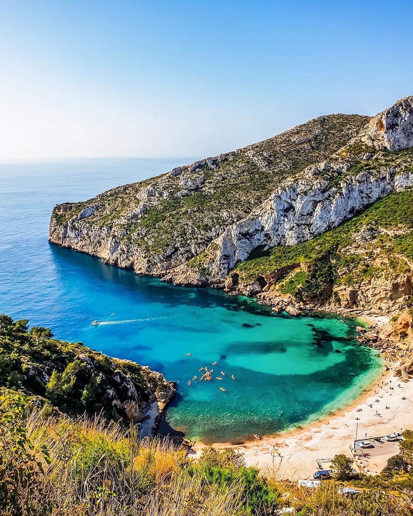 Turquoise cove between pine-covered cliffs in Jávea