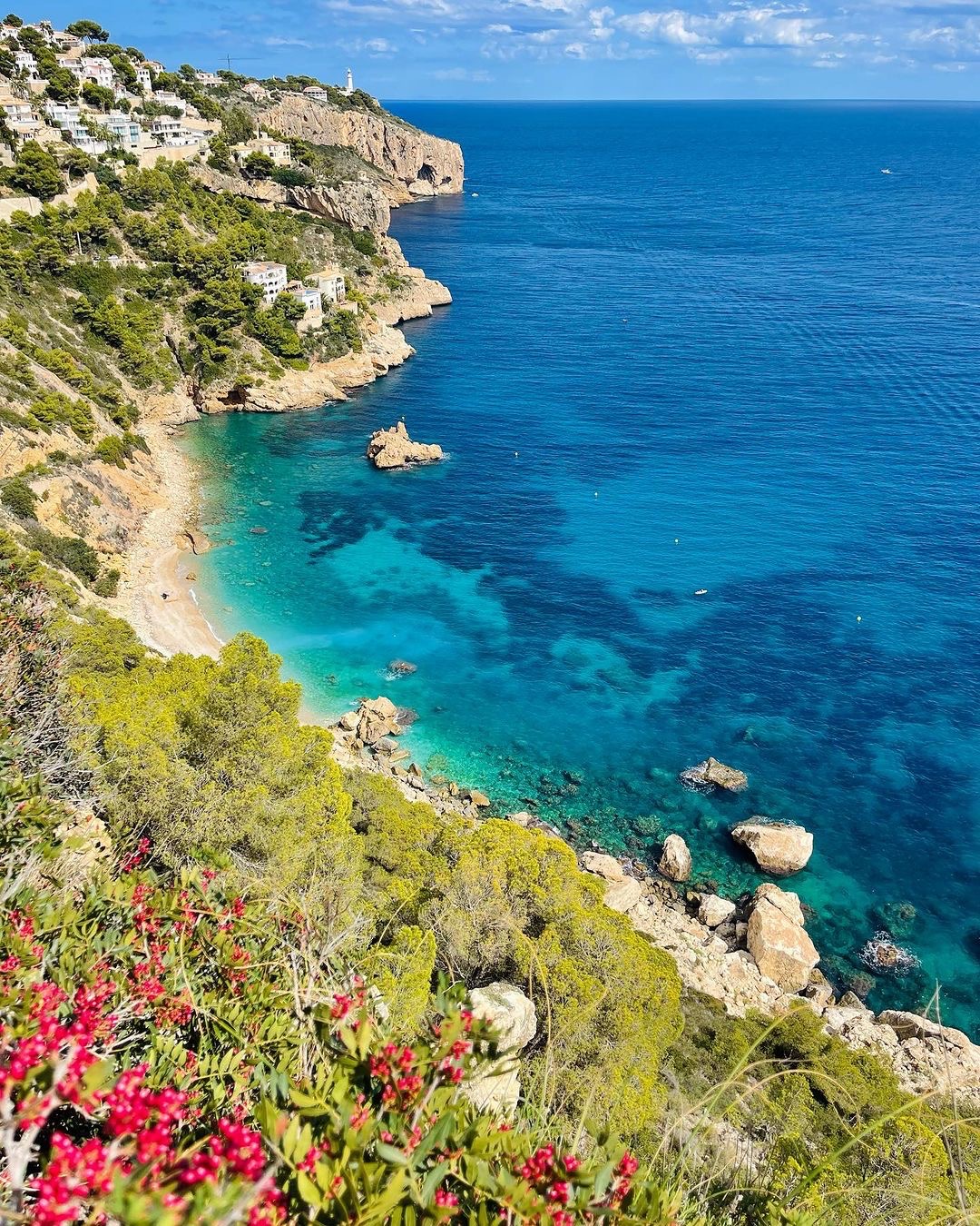 Acantilados con casas blancas y flores sobre una cala de Jávea